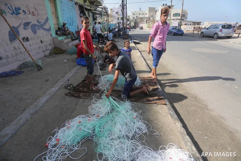 A Palestinian fisherman fixes a fishing net, at the beach in Gaza City, on Sept. 21, 2016. Photo by Mohammed Asad