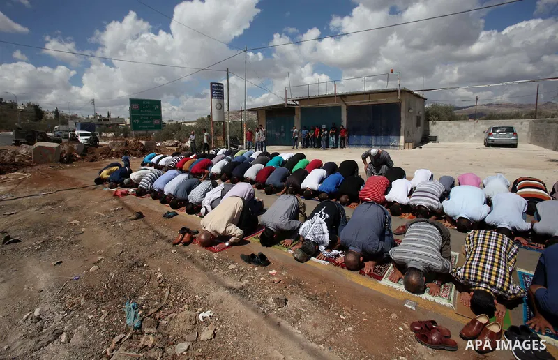 Palestinians perform Friday prayers, as Israeli soldiers look on, next to the Beta Junction east West Bank city of Nablus, on September 23, 2016, to protest against the closure of the entrance of the Beta village by the...