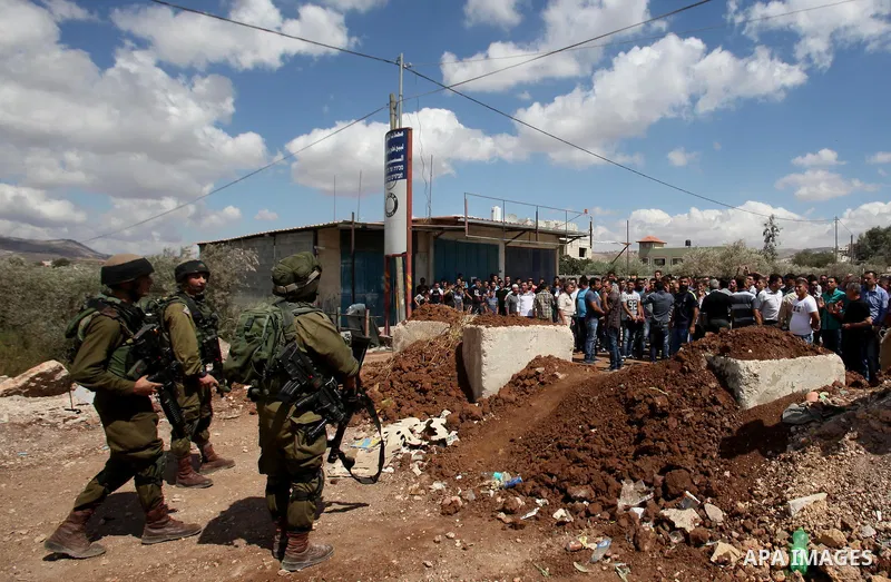 Palestinian protesters take part during a protest in front of Israeli soldiers against the closure of the entrance of the Beta village by the Israeli army following Friday prayers, next to the Beta Junction east West Ban...