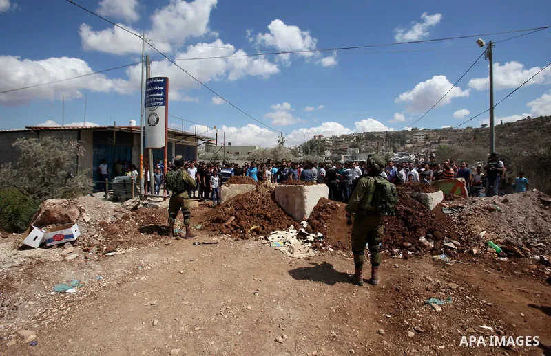 Palestinian protesters take part during a protest in front of Israeli soldiers against the closure of the entrance of the Beta village by the Israeli army following Friday prayers, next to the Beta Junction east West Ban...