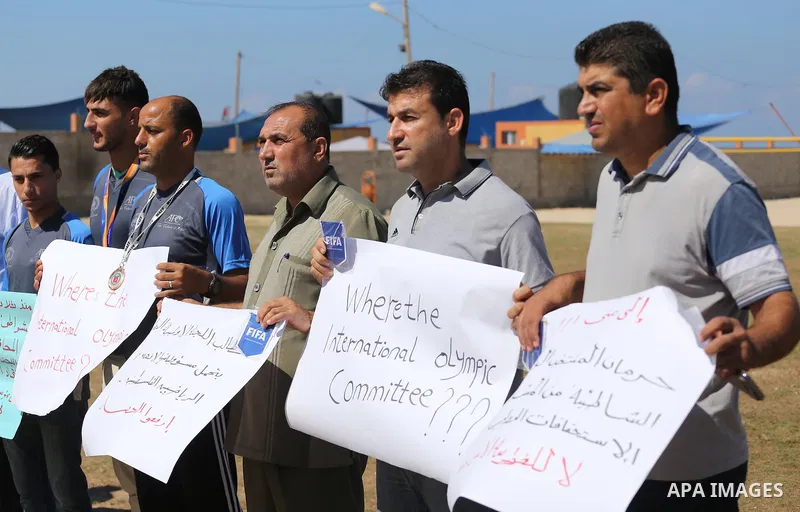 Palestinian sportsmen hold banners during a protest against the Israeli authorities to prevent their travel to Vietnam through the Erez crossing, in Gaza city, on Sept. 24, 2016. Photo by Mohammed Asad