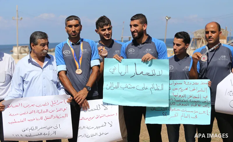 Palestinian sportsmen hold banners during a protest against the Israeli authorities to prevent their travel to Vietnam through the Erez crossing, in Gaza city, on Sept. 24, 2016. Photo by Mohammed Asad
