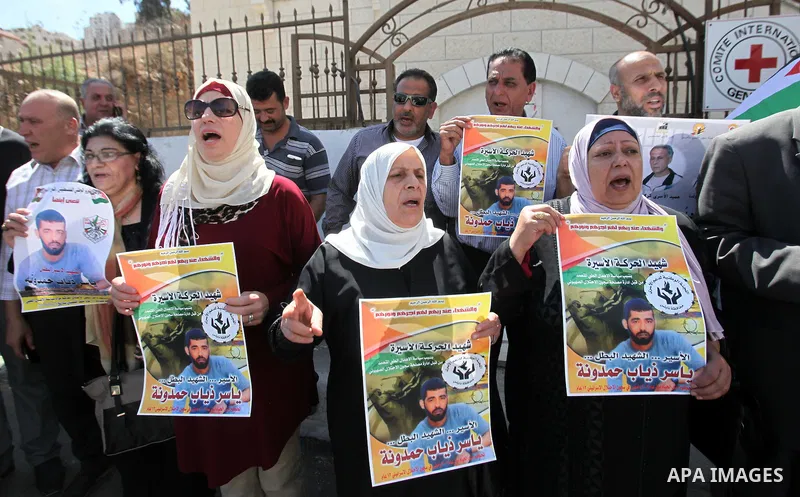 Palestinians hold pictures of Yassir Hamduni, who died of a stroke on 25 September in the Israeli prison of Ramon, as they protest outside the headquarters of the International Committee of the Red Cross (ICRC) in West B...