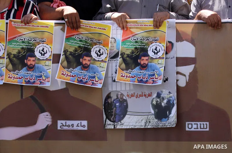 Palestinians hold pictures of Yassir Hamduni, who died of a stroke on 25 September in the Israeli prison of Ramon, as they protest outside the headquarters of the International Committee of the Red Cross (ICRC) in West B...