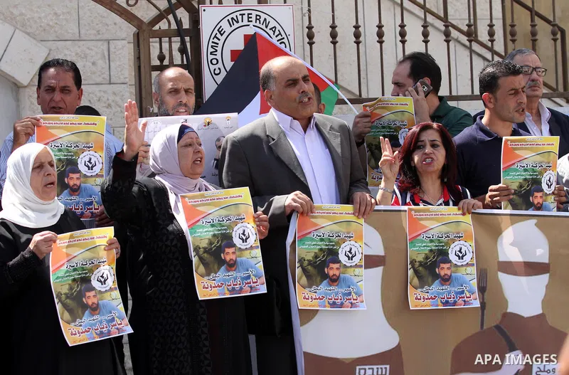 Palestinians hold pictures of Yassir Hamduni, who died of a stroke on 25 September in the Israeli prison of Ramon, as they protest outside the headquarters of the International Committee of the Red Cross (ICRC) in West B...