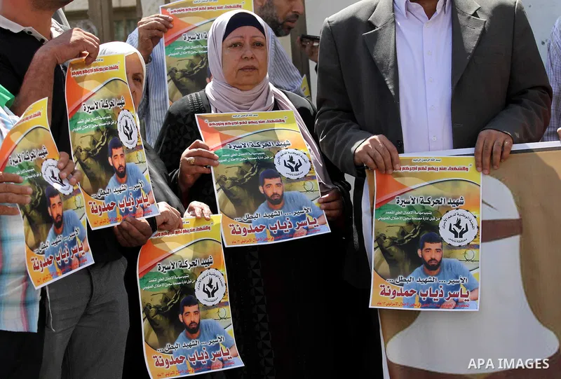 Palestinians hold pictures of Yassir Hamduni, who died of a stroke on 25 September in the Israeli prison of Ramon, as they protest outside the headquarters of the International Committee of the Red Cross (ICRC) in West B...
