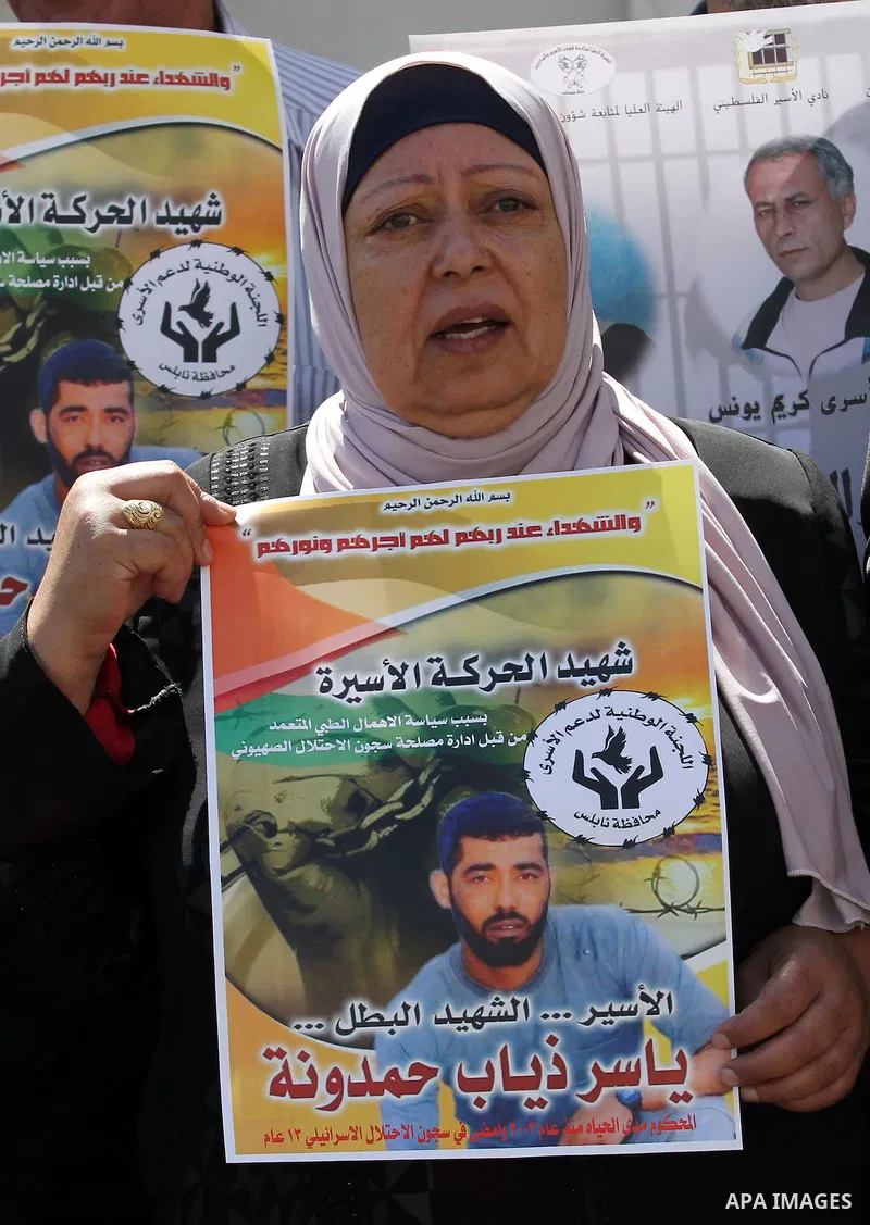 Palestinians hold pictures of Yassir Hamduni, who died of a stroke on 25 September in the Israeli prison of Ramon, as they protest outside the headquarters of the International Committee of the Red Cross (ICRC) in West B...