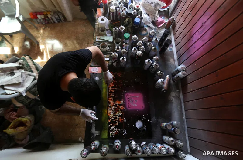 A Palestinian artist Khaled Salama, 27, paints on glass pots using colored sand, at his work shop in the West Bank city of Salfit, on Sep. 27, 2016. Photo by Shadi Hatem