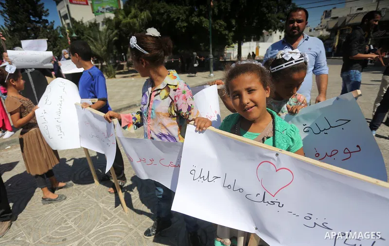 Palestinians hold banners during a protest due to prevent Ms. Jalila Dahlan from entering the Gaza Strip, in Gaza city, on Sept. 28, 2016. Photo by Mohammed Asad