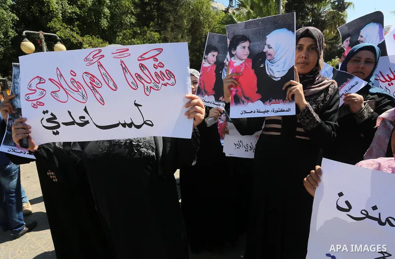 Palestinians hold banners during a protest due to prevent Ms. Jalila Dahlan from entering the Gaza Strip, in Gaza city, on Sept. 28, 2016. Photo by Mohammed Asad