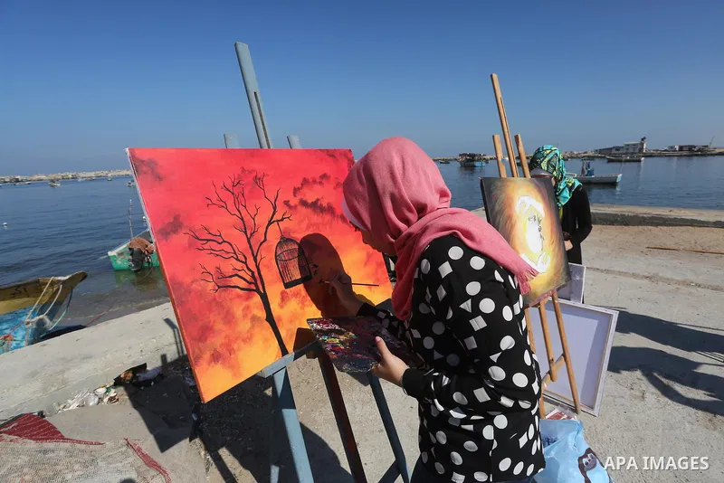 A Palestinian artist paints artwork during a protest supporting of a Gaza-bound flotilla of international activists attempting to break the Gaza blockade, at Gaza seaport on September 29, 2016. Photo by Mohammed Asad