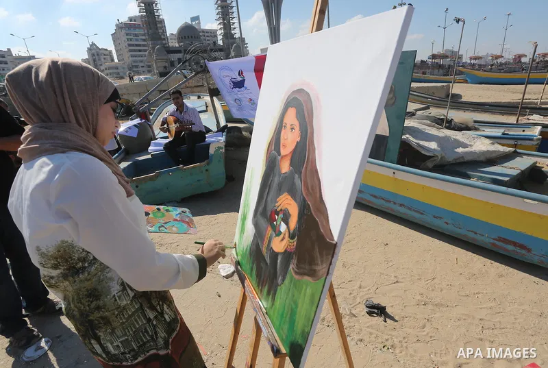 A Palestinian artist paints artwork during a protest supporting of a Gaza-bound flotilla of international activists attempting to break the Gaza blockade, at Gaza seaport on September 29, 2016. Photo by Mohammed Asad