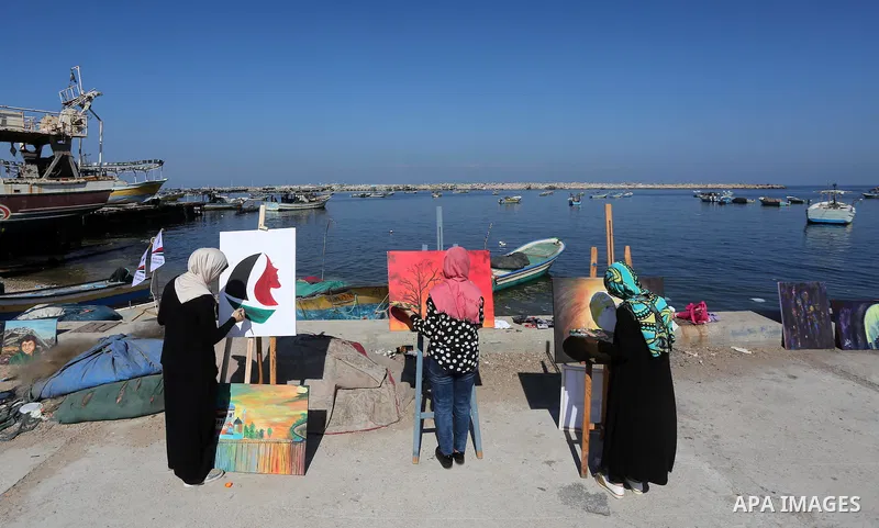 Palestinian artists paint artwork during a protest supporting of a Gaza-bound flotilla of international activists attempting to break the Gaza blockade, at Gaza seaport on September 29, 2016. Photo by Mohammed Asad