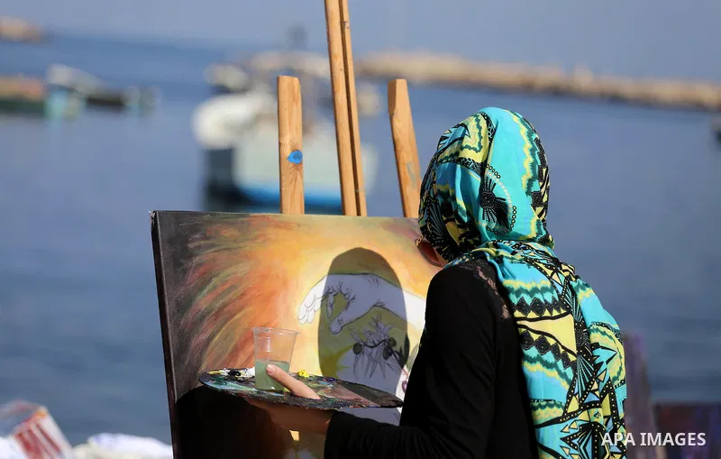A Palestinian artist paints artwork during a protest supporting of a Gaza-bound flotilla of international activists attempting to break the Gaza blockade, at Gaza seaport on September 29, 2016. Photo by Mohammed Asad