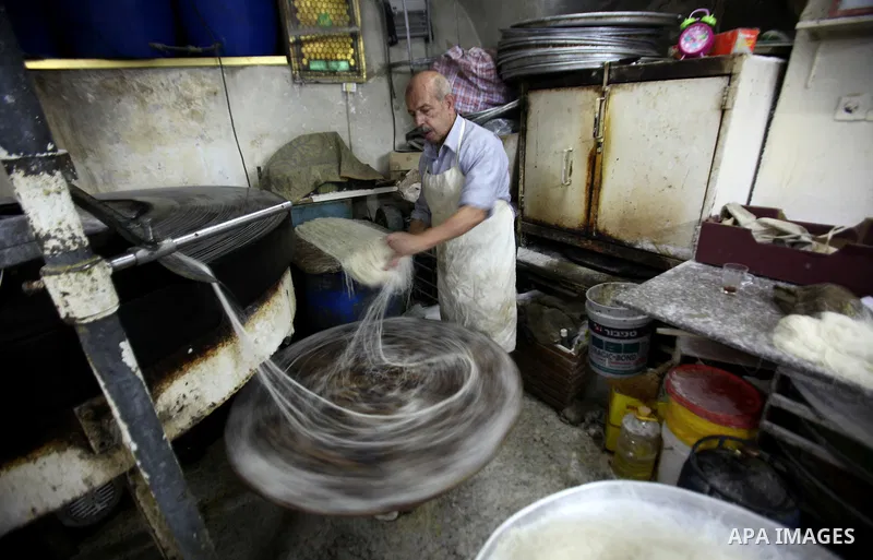 Palestinian Belal al-Zaqa, 64, prepares Kunafa, a traditional and favorite local sweet at his shop, in the West Bank city of Nablus on Sep. 29, 2016. Photo by Nedal Eshtayah