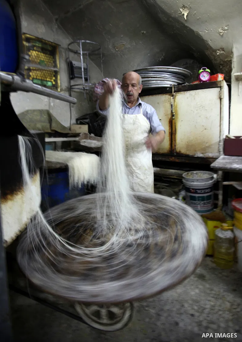 Palestinian Belal al-Zaqa, 64, prepares Kunafa, a traditional and favorite local sweet at his shop, in the West Bank city of Nablus on Sep. 29, 2016. Photo by Nedal Eshtayah