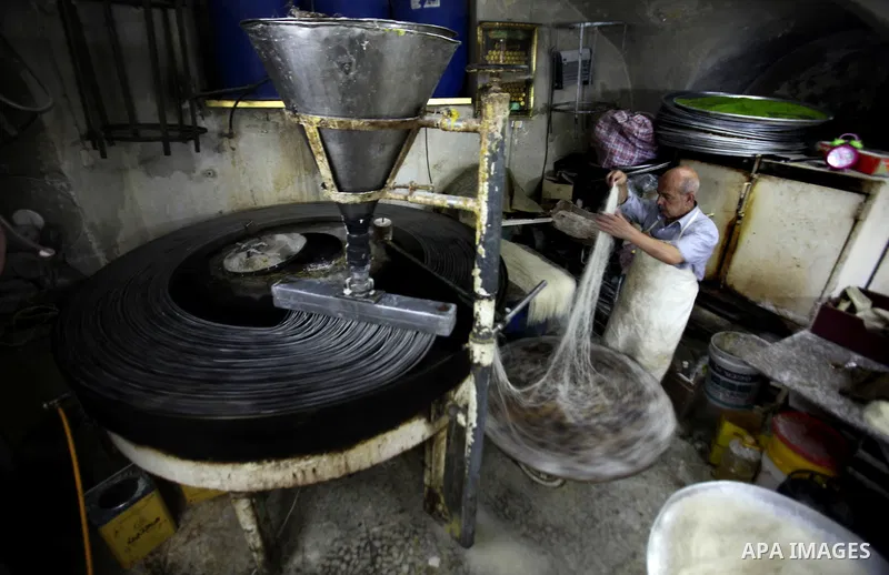 Palestinian Belal al-Zaqa, 64, prepares Kunafa, a traditional and favorite local sweet at his shop, in the West Bank city of Nablus on Sep. 29, 2016. Photo by Nedal Eshtayah