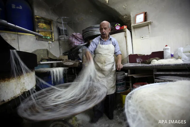 Palestinian Belal al-Zaqa, 64, prepares Kunafa, a traditional and favorite local sweet at his shop, in the West Bank city of Nablus on Sep. 29, 2016. Photo by Nedal Eshtayah