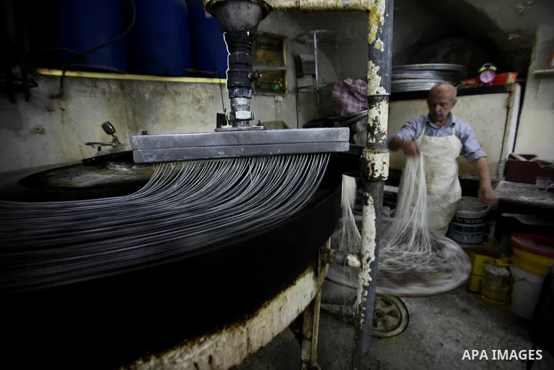 Palestinian Belal al-Zaqa, 64, prepares Kunafa, a traditional and favorite local sweet at his shop, in the West Bank city of Nablus on Sep. 29, 2016. Photo by Nedal Eshtayah