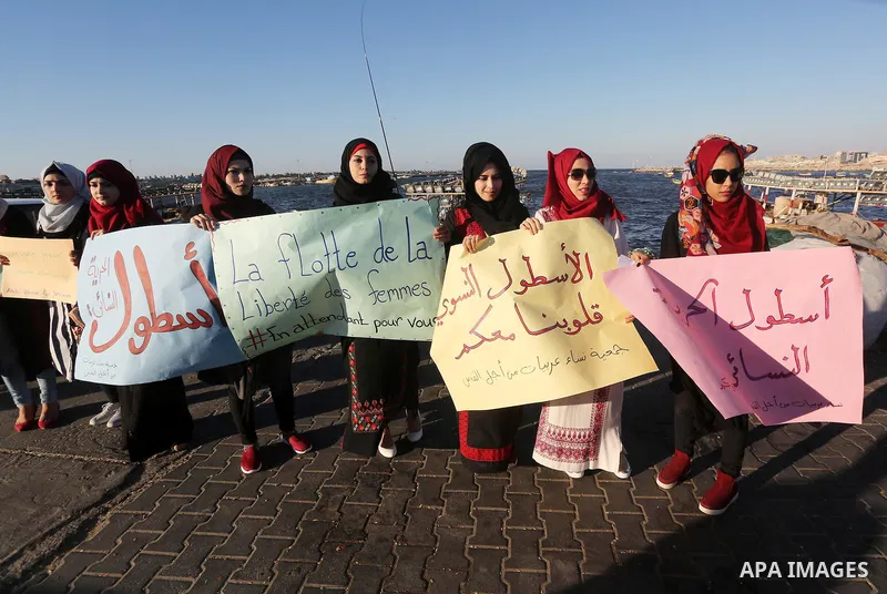 Palestinians hold banners during a protest supporting of a Gaza-bound flotilla of international activists attempting to break the Gaza blockade, at Gaza seaport on September 29, 2016. Photo by Mohammed Asad