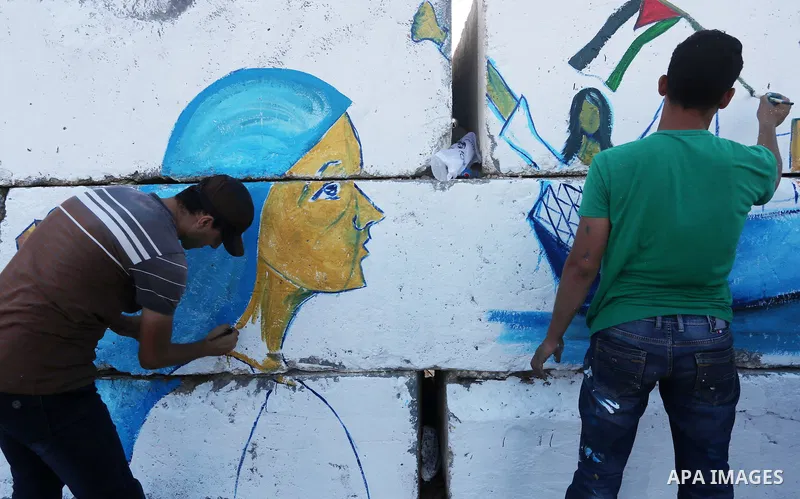 Palestinian artists paint a mural during a protest supporting of a Gaza-bound flotilla of international activists attempting to break the Gaza blockade, at Gaza seaport on September 29, 2016. Photo by Mohammed Asad