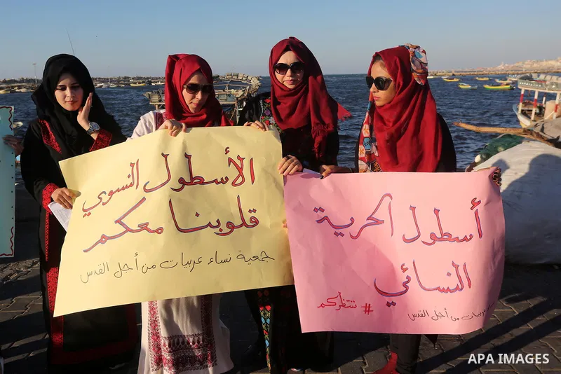 Palestinians hold banners during a protest supporting of a Gaza-bound flotilla of international activists attempting to break the Gaza blockade, at Gaza seaport on September 29, 2016. Photo by Mohammed Asad