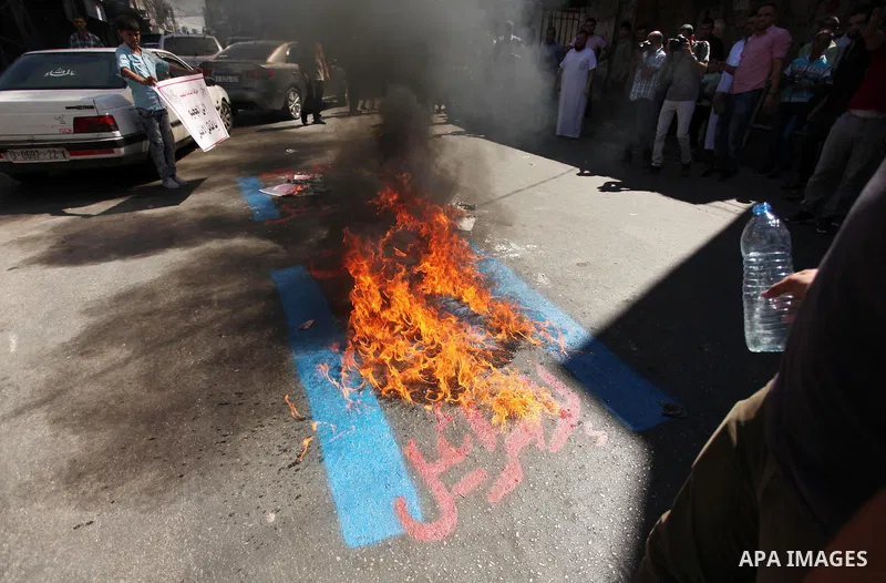Palestinians burn a crossed poster of former Israeli President Shimon Peres, reading "murderer", during a rally following Friday prayers in Gaza City September 30, 2016. Photo by Ashraf Amra