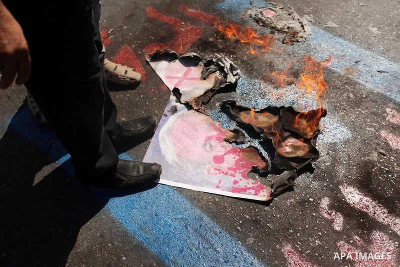 Palestinians burn a crossed poster of former Israeli President Shimon Peres, reading "murderer", during a rally following Friday prayers in Gaza City September 30, 2016. Photo by Ashraf Amra