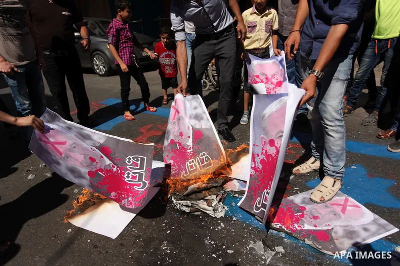 Palestinians burn a crossed poster of former Israeli President Shimon Peres, reading "murderer", during a rally following Friday prayers in Gaza City September 30, 2016. Photo by Ashraf Amra