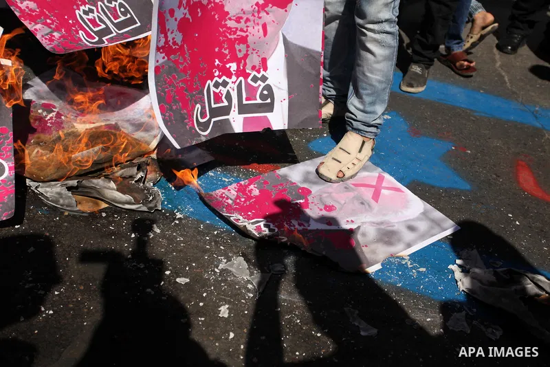 A Palestinian steps on a crossed poster of former Israeli President Shimon Peres, reading "Murderer", during a rally following Friday prayers in Gaza City September 30, 2016. Photo by Ashraf Amra