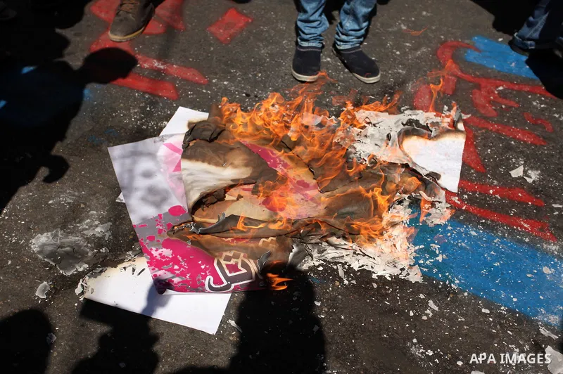 Palestinians burn a crossed poster of former Israeli President Shimon Peres, reading "murderer", during a rally following Friday prayers in Gaza City September 30, 2016. Photo by Ashraf Amra