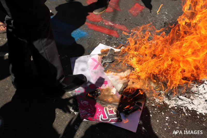 Palestinians burn a crossed poster of former Israeli President Shimon Peres, reading "murderer", during a rally following Friday prayers in Gaza City September 30, 2016. Photo by Ashraf Amra