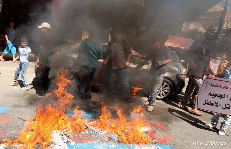Palestinians burn a crossed poster of former Israeli President Shimon Peres, reading "murderer", during a rally following Friday prayers in Gaza City September 30, 2016. Photo by Ashraf Amra