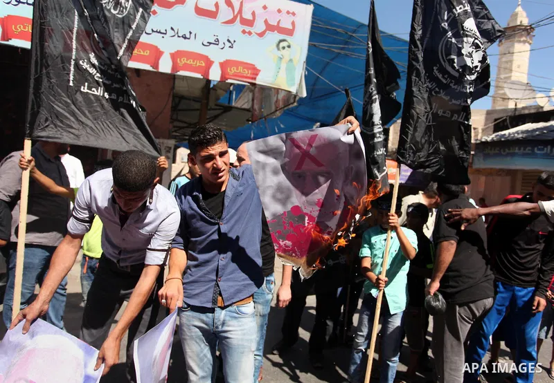 Palestinians burn a crossed poster of former Israeli President Shimon Peres, reading "murderer", during a rally following Friday prayers in Gaza City September 30, 2016. Photo by Ashraf Amra