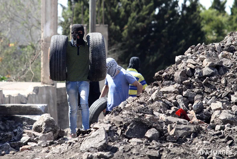 A Palestinian protester carries tires during clashes with Israeli security forces following a weekly demonstration against the expropriation of Palestinian land by Israel on Sep. 30, 2016, in the village of Kfar Qaddum,...