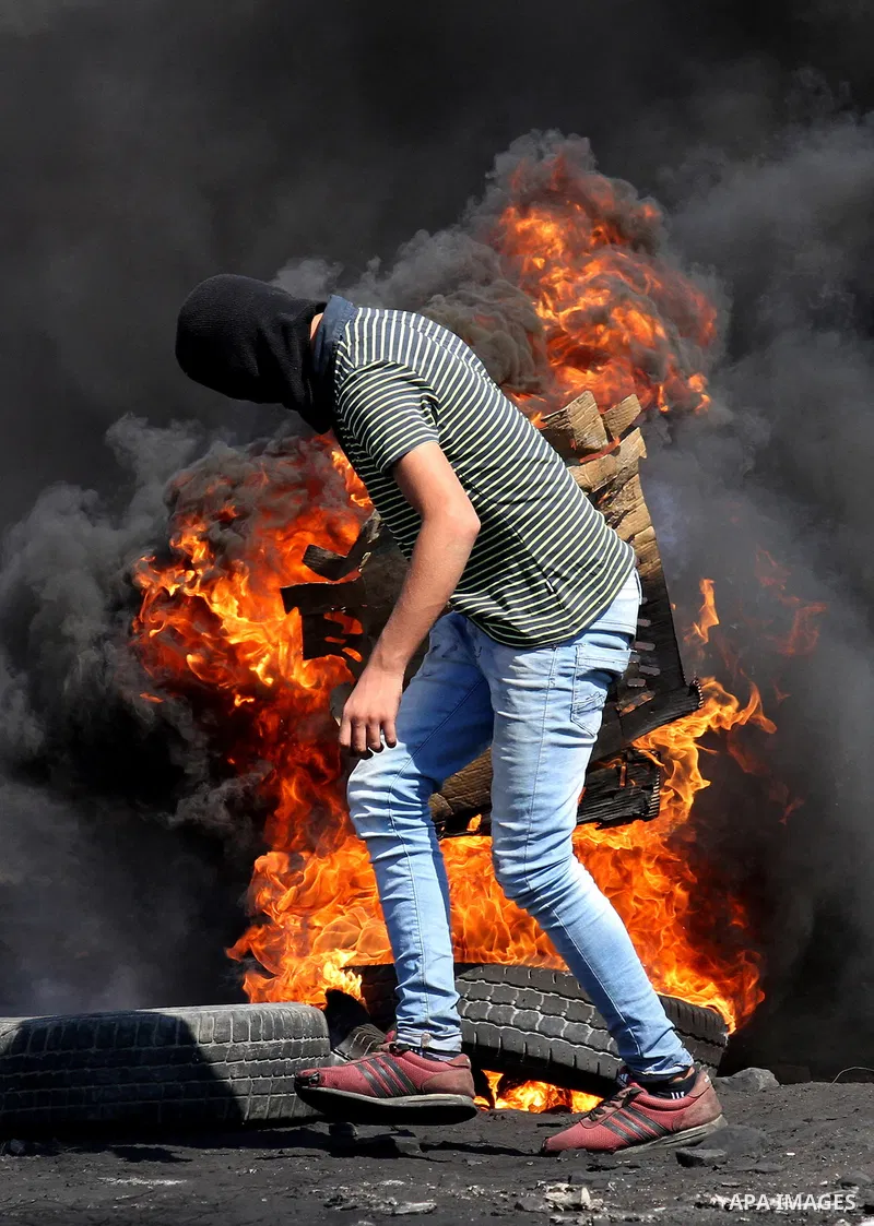 A Palestinian protester burns tires during clashes with Israeli security forces following a weekly demonstration against the expropriation of Palestinian land by Israel on Sep. 30, 2016, in the village of Kfar Qaddum, ne...