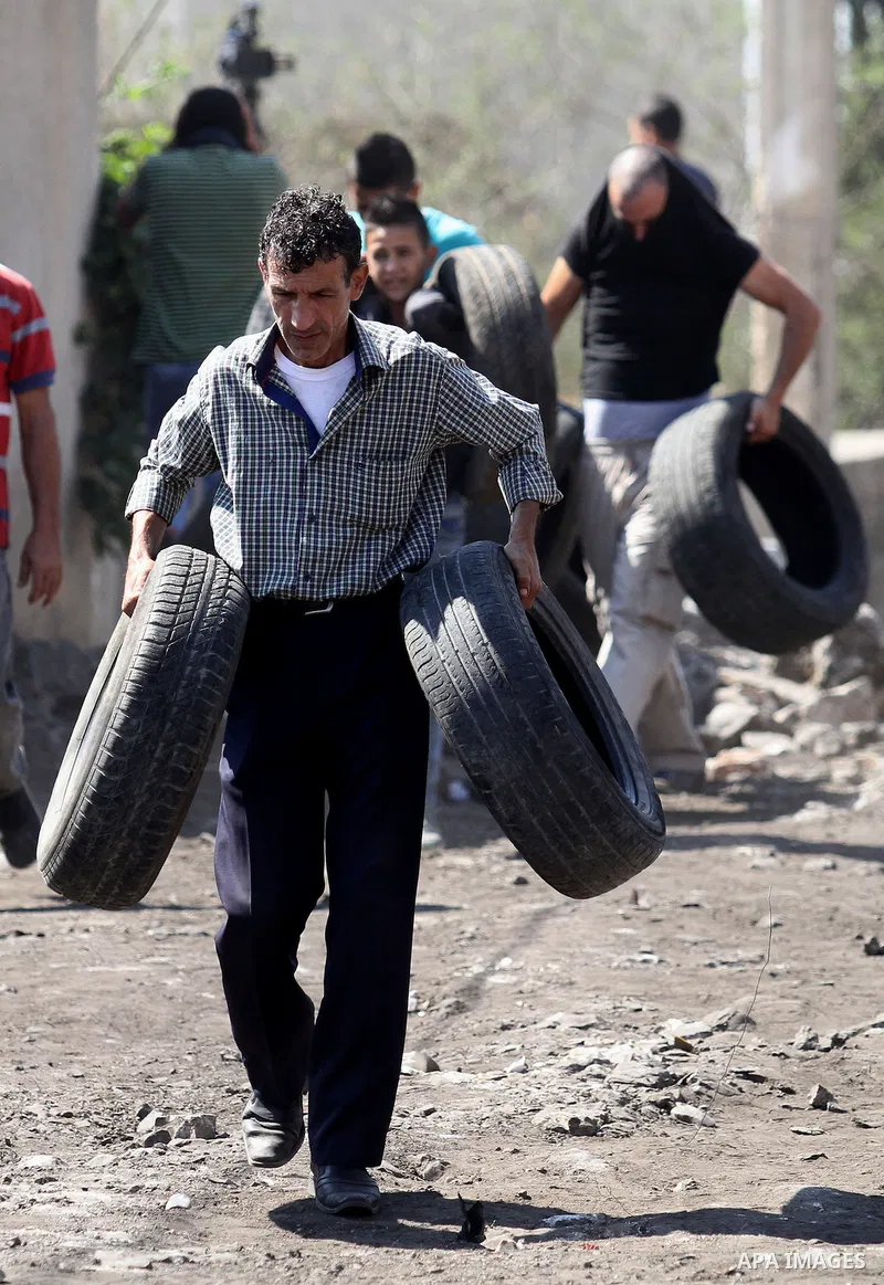 A Palestinian protester carries tires during clashes with Israeli security forces following a weekly demonstration against the expropriation of Palestinian land by Israel on Sep. 30, 2016, in the village of Kfar Qaddum,...