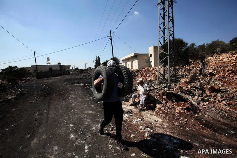 A Palestinian protester carries tires during clashes with Israeli security forces following a weekly demonstration against the expropriation of Palestinian land by Israel on Sep. 30, 2016, in the village of Kfar Qaddum,...