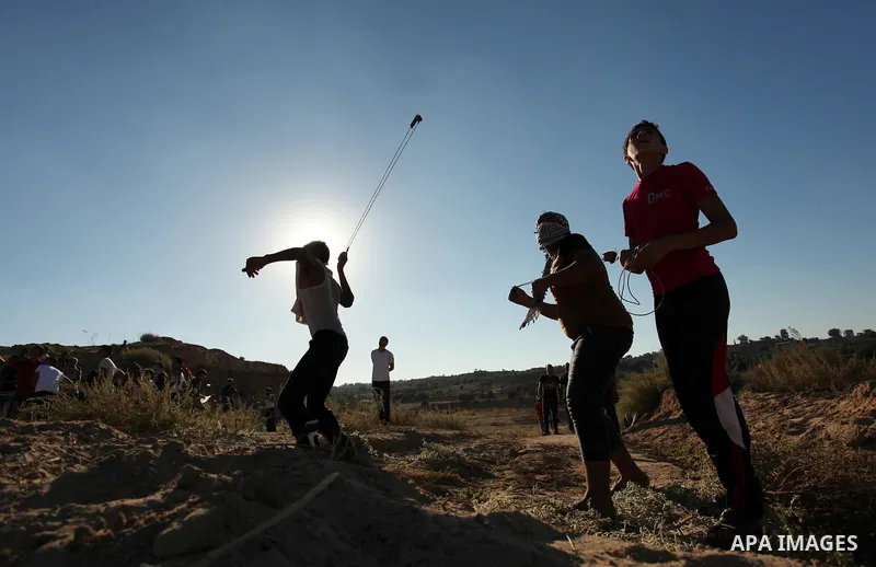 A Palestinian protester uses a slingshot to hurl stones toward Israeli security forces during clashes near the border between Israel and Central Gaza Strip east of Bureij on Sep. 30, 2016. Photo by Ashraf Amra
