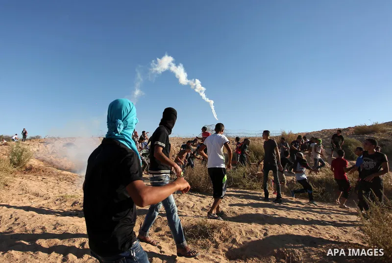 Palestinian protesters take cover during clashes with Israeli security forces near the border between Israel and Central Gaza Strip east of Bureij on Sep. 30, 2016. Photo by Ashraf Amra
