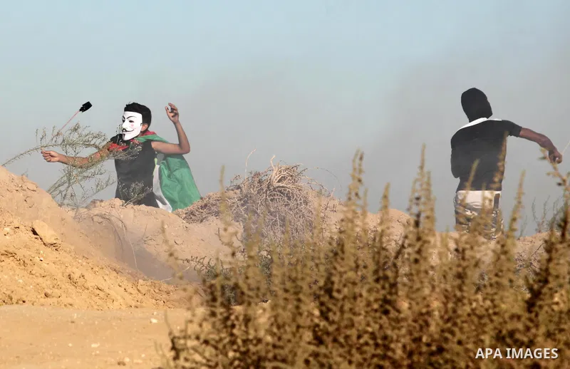 Palestinian protesters use a slingshot to hurl stones toward Israeli security forces during clashes near the border between Israel and Central Gaza Strip east of Bureij on Sep. 30, 2016. Photo by Ashraf Amra
