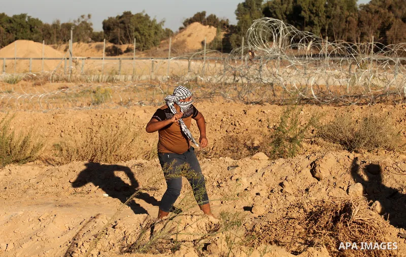 A Palestinian protester uses a slingshot to hurl stones toward Israeli security forces during clashes near the border between Israel and Central Gaza Strip east of Bureij on Sep. 30, 2016. Photo by Ashraf Amra