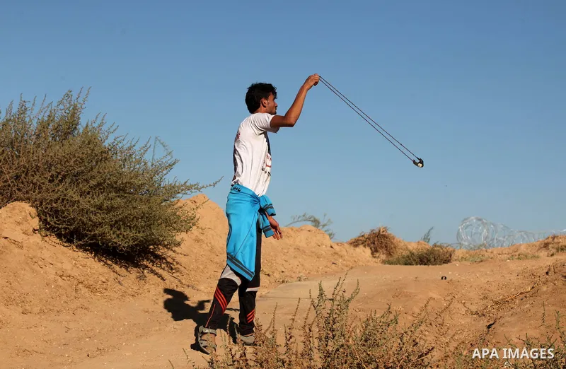 A Palestinian protester uses a slingshot to hurl stones toward Israeli security forces during clashes near the border between Israel and Central Gaza Strip east of Bureij on Sep. 30, 2016. Photo by Ashraf Amra
