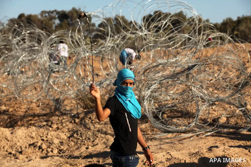 A Palestinian protester uses a slingshot to hurl stones toward Israeli security forces during clashes near the border between Israel and Central Gaza Strip east of Bureij on Sep. 30, 2016. Photo by Ashraf Amra