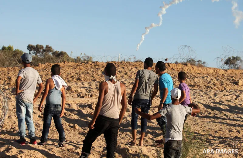 Palestinian protesters take cover during clashes with Israeli security forces near the border between Israel and Central Gaza Strip east of Bureij on Sep. 30, 2016. Photo by Ashraf Amra