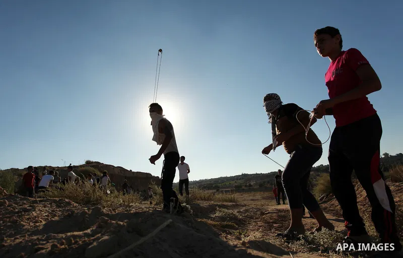 A Palestinian protester uses a slingshot to hurl stones toward Israeli security forces during clashes near the border between Israel and Central Gaza Strip east of Bureij on Sep. 30, 2016. Photo by Ashraf Amra