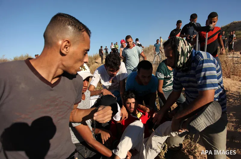 Palestinian protesters carry a wounded comrade during clashes with Israeli security forces near the border between Israel and Central Gaza Strip east of Bureij on Sep. 30, 2016. Photo by Ashraf Amra