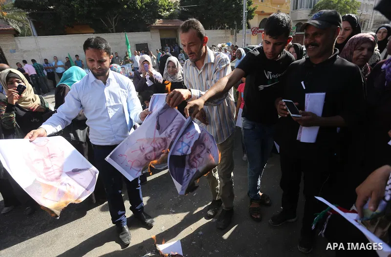 Palestinians burn posters of former Israeli President Shimon Peres during a protest, in front of Red cross office in Gaza city, on Oct. 03, 2016. Photo by Mohammed Asad