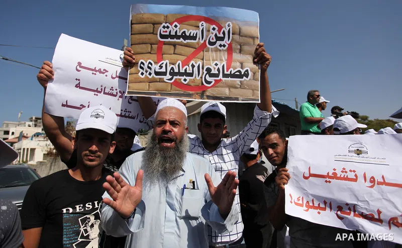 Palestinian owners of factories hold banners during a protest against israeli blockade on operations their factories, in front of the headquarter United Nation "UNSCO", in Gaza city, on October 4, 2016. Photo by Ashraf A...