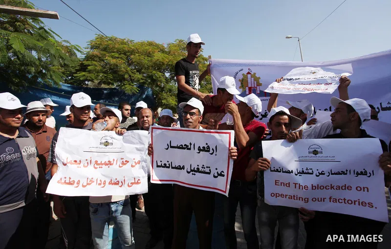 Palestinian owners of factories hold banners during a protest against israeli blockade on operations their factories, in front of the headquarter United Nation "UNSCO", in Gaza city, on October 4, 2016. Photo by Ashraf A...